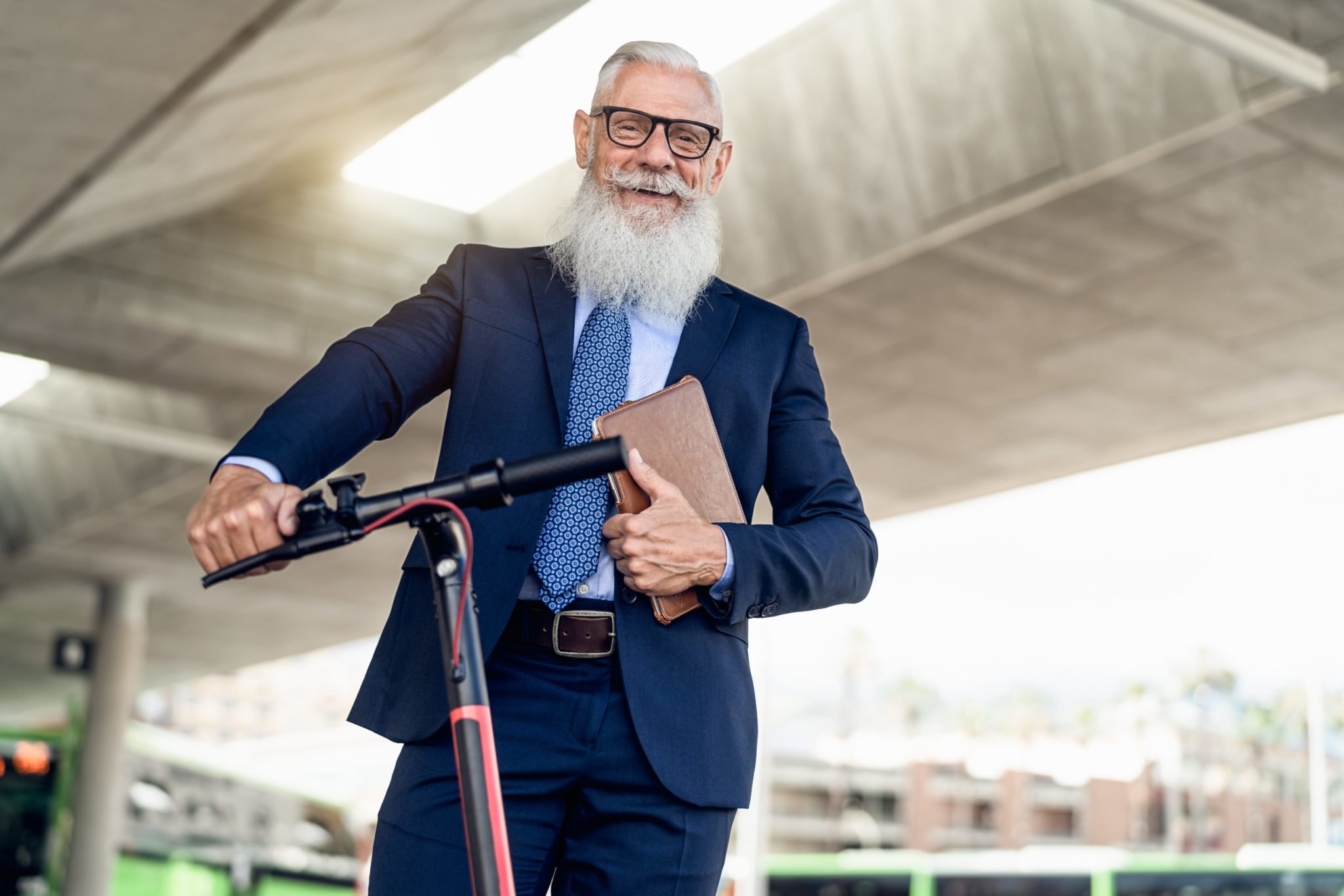 Senior business man going to work with electric scooter around city center
